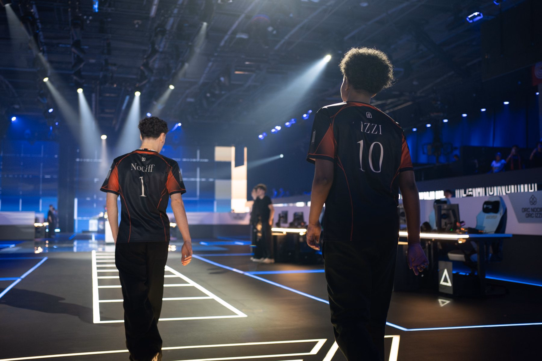 Nociff and Izzi, seen from behind in jerseys numbered 1 and 10, walk into the arena under the lights.